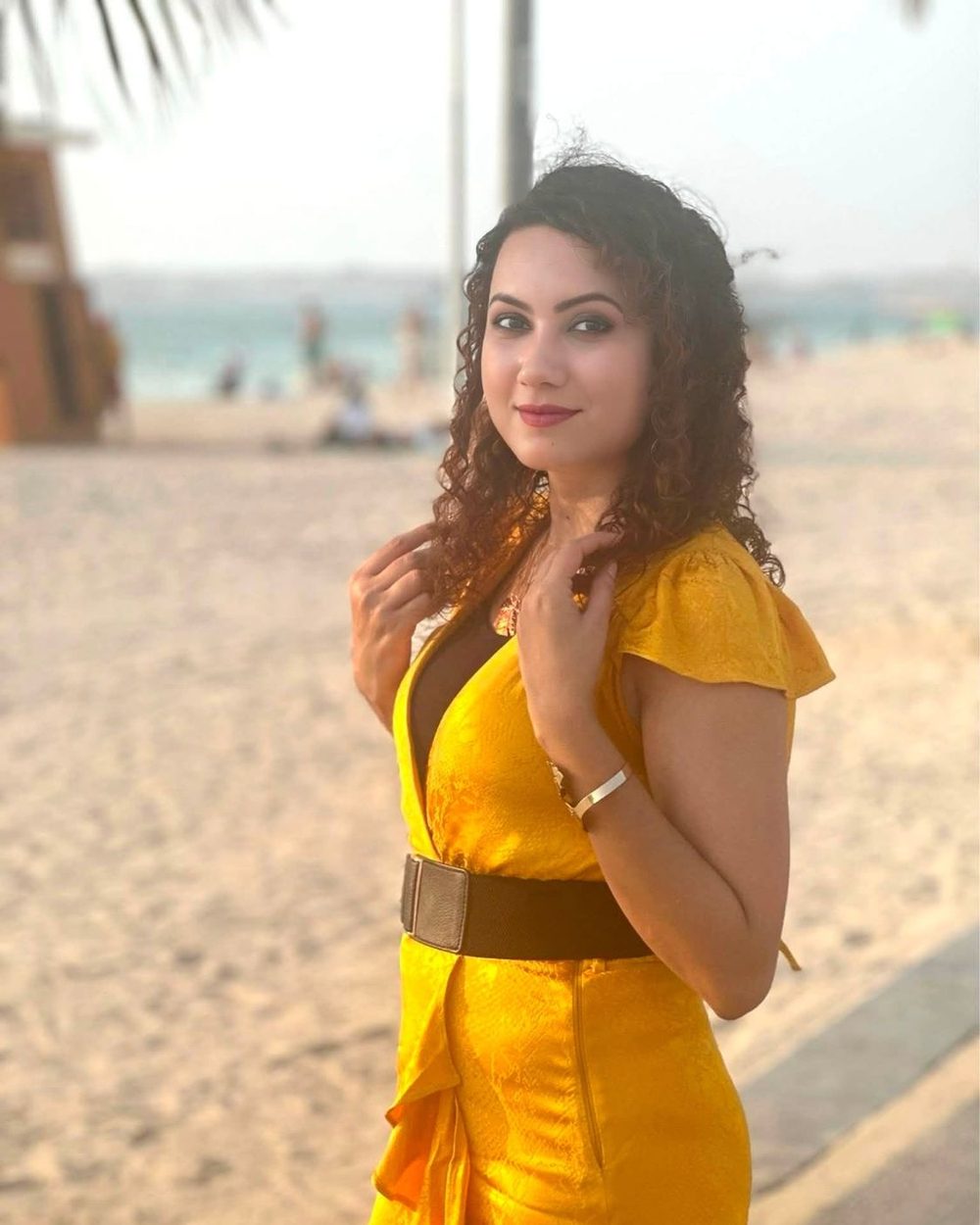 Jannatul Ferdaus in a yellow dress on a Dubai beach, looking over her shoulder toward the camera